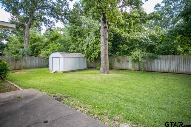 a view of a backyard with large trees and wooden fence