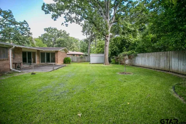 a view of a house with backyard and a tree