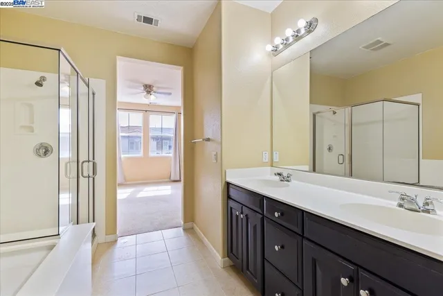 a bathroom with a double vanity sink a large mirror and shower