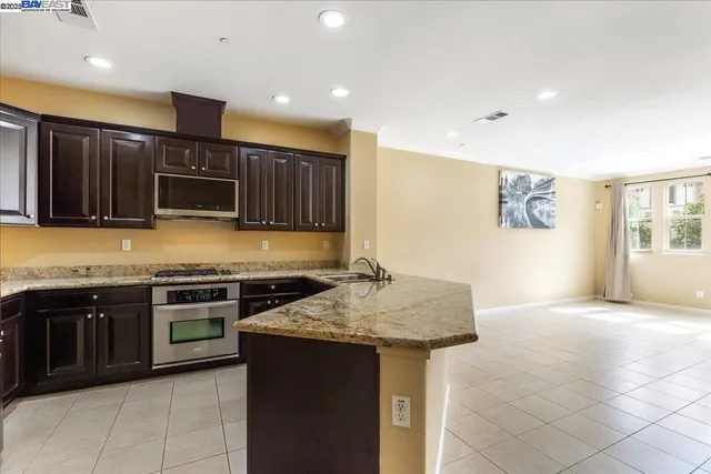 a kitchen with stainless steel appliances granite countertop a stove top oven a sink and dishwasher
