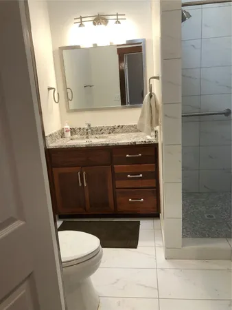 a bathroom with a granite countertop toilet a sink and a mirror