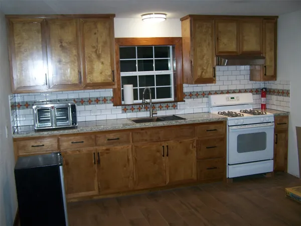 a kitchen with stainless steel appliances granite countertop a stove a sink and dishwasher next to a window