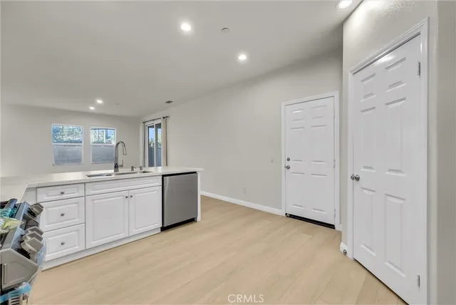 wooden floor with white cabinets and window