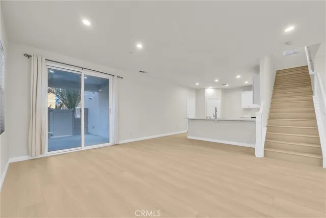 a view of an empty room with kitchen and a window