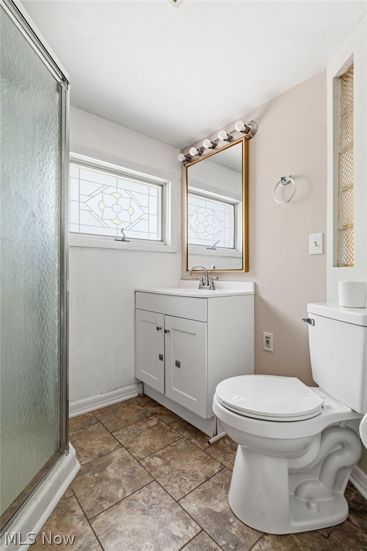 4449 18th Street Northwest Canton, OH 44708 - Photo 17 of 25 Bathroom featuring a glass-enclosed shower, white vanity with integrated sink, patterned stained glass window, and tiled flooring