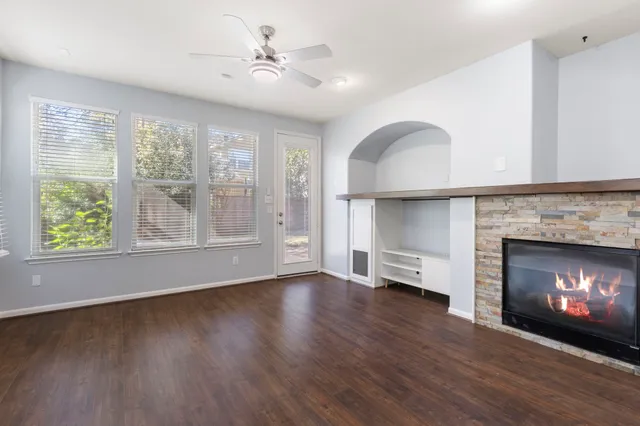 a view of an empty room with wooden floor fireplace and a window