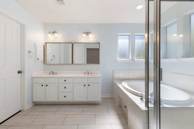 a bathroom with a granite countertop double vanity sink mirror and bathtub