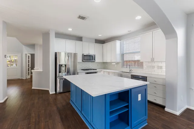 a kitchen with a sink a refrigerator a stove and white cabinets with wooden floor