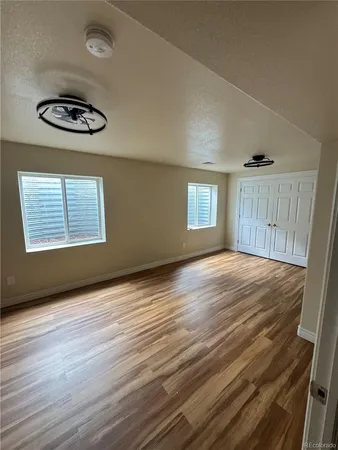 an empty room with wooden floor and windows