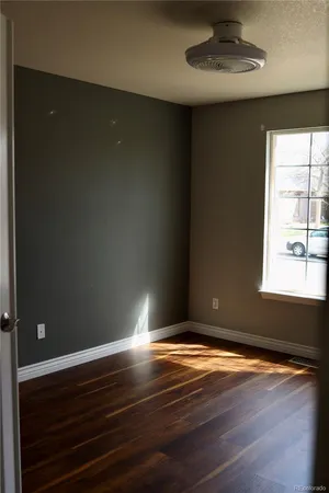 a view of empty room with wooden floor and fan
