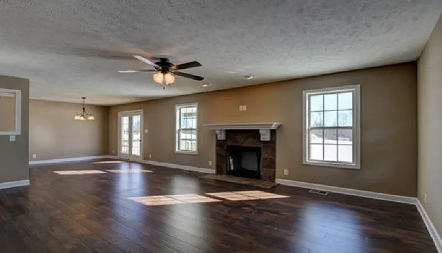 an empty room with wooden floor fireplace and windows