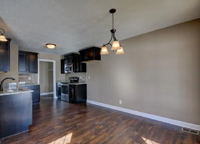 a kitchen with kitchen island stainless steel appliances a sink cabinets and wooden floor