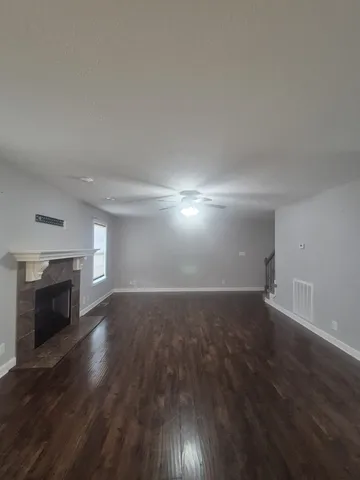 an empty room with wooden floor fireplace and windows