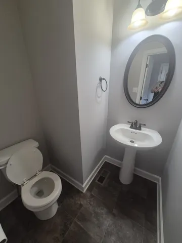 a bathroom with a toilet a sink and mirror