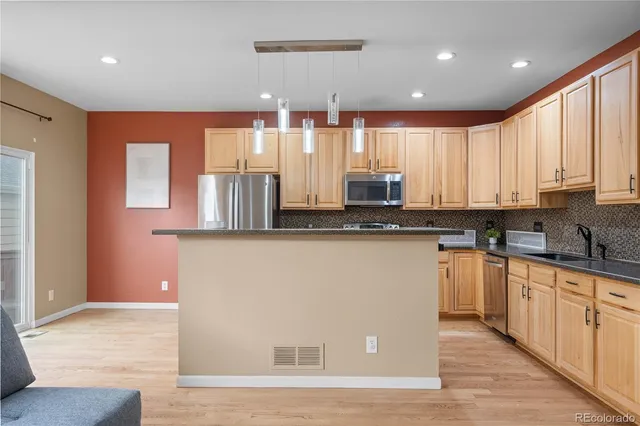 a kitchen with stainless steel appliances granite countertop a refrigerator a stove a sink dishwasher and a fireplace with wooden floor