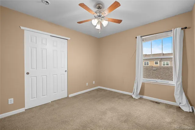 an empty room with a chandelier fan and windows
