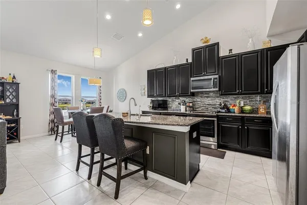a kitchen with stainless steel appliances granite countertop a table chairs sink refrigerator and microwave