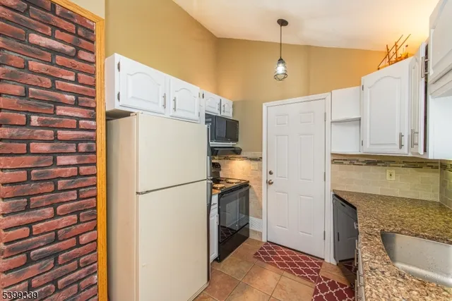 a kitchen with stainless steel appliances granite countertop a refrigerator a oven and white cabinets with granite countertops