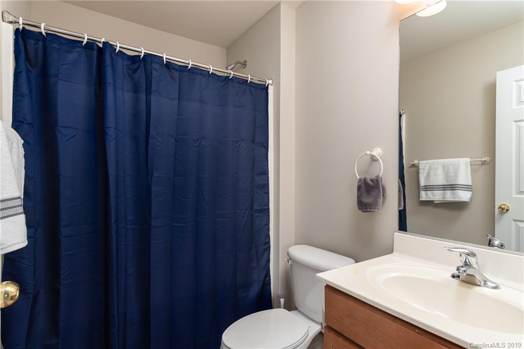 4854 Prosperity Ridge Road Charlotte, NC 28269 - Photo 18 of 22 a bathroom with a sink a toilet a mirror and shower curtain