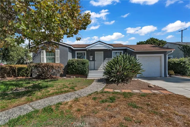 a view of a house with a yard and large tree