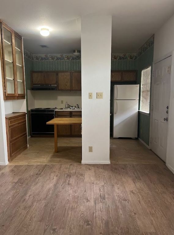 2813 1/2 Rio Grande Street, Unit 5 Austin, TX 78701 - Photo 4 of 21 Kitchen featuring freestanding refrigerator, light wood-style floors, black stove, and brown cabinets