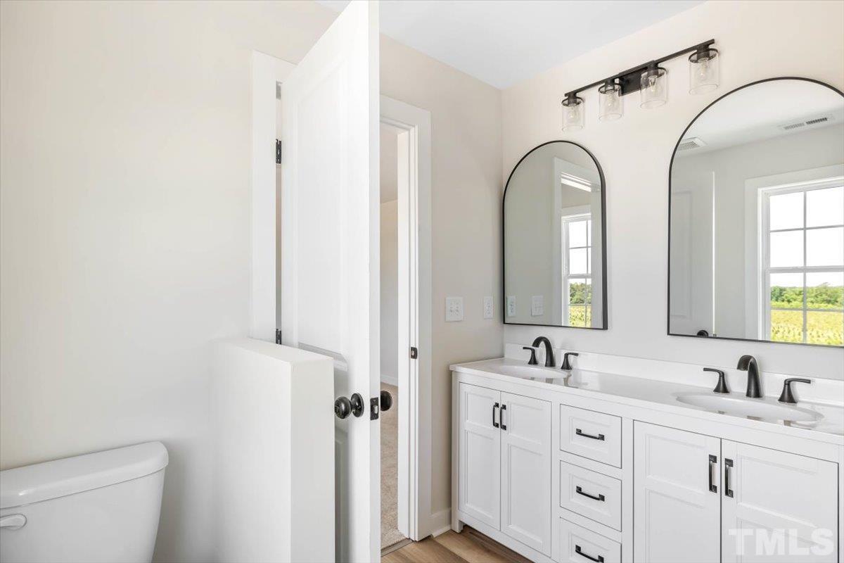 2075 Highway 55 Coats, NC 27521 - Photo 21 of 24 a bathroom with a double vanity sink a mirror and a toilet