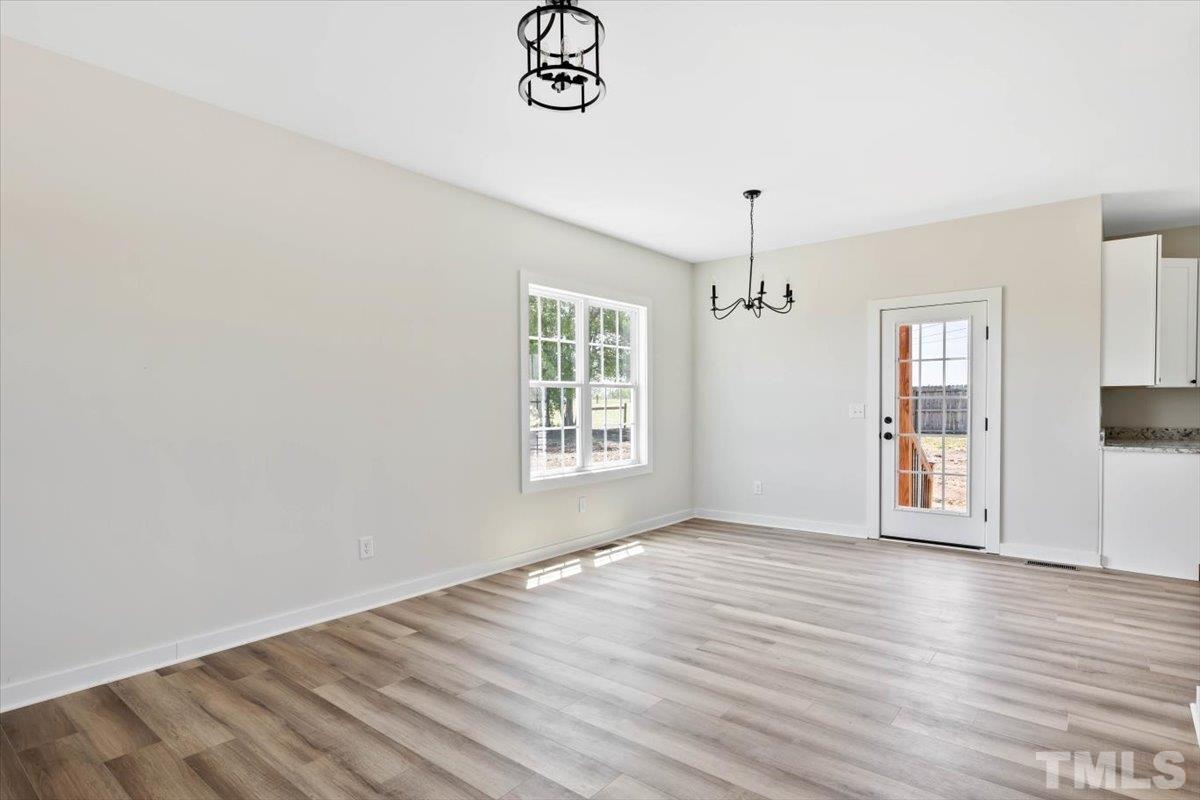2075 Highway 55 Coats, NC 27521 - Photo 5 of 24 an empty room with wooden floor chandelier fan and windows