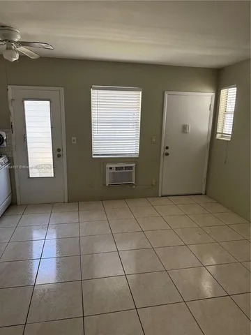 a view of an empty room with window and chandelier