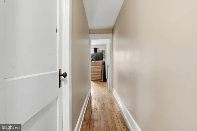 a view of a hallway with wooden floor and a bathroom