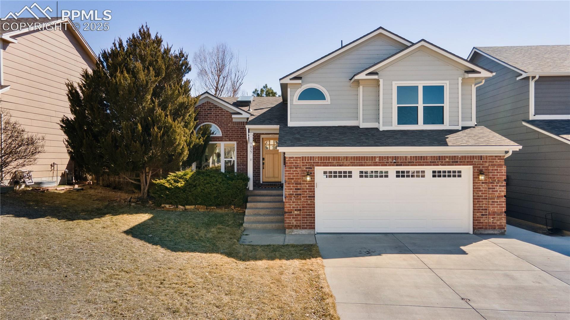 7827 Swiftrun Road Colorado Springs, CO 80920 - Photo 1 of 48 View of front of property featuring a garage, brick siding, concrete driveway, roof with shingles, and a front yard