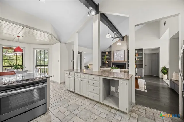 a kitchen with stainless steel appliances kitchen island granite countertop a stove and white cabinets