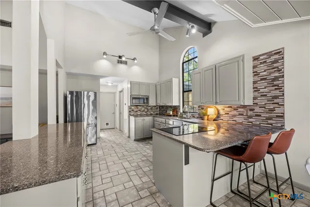a kitchen with kitchen island a counter top space a sink stainless steel appliances and cabinets