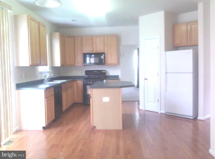 a kitchen with stainless steel appliances granite countertop a sink a stove a refrigerator a center island and a window