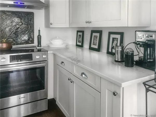 a kitchen with granite countertop white cabinets and stainless steel appliances