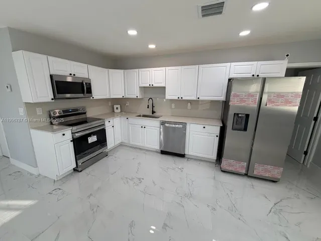 a kitchen with stainless steel appliances granite countertop a refrigerator a stove a sink and a microwave