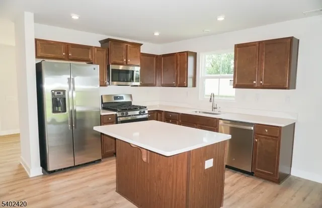 a kitchen with stainless steel appliances granite countertop a sink a microwave a refrigerator and a stove