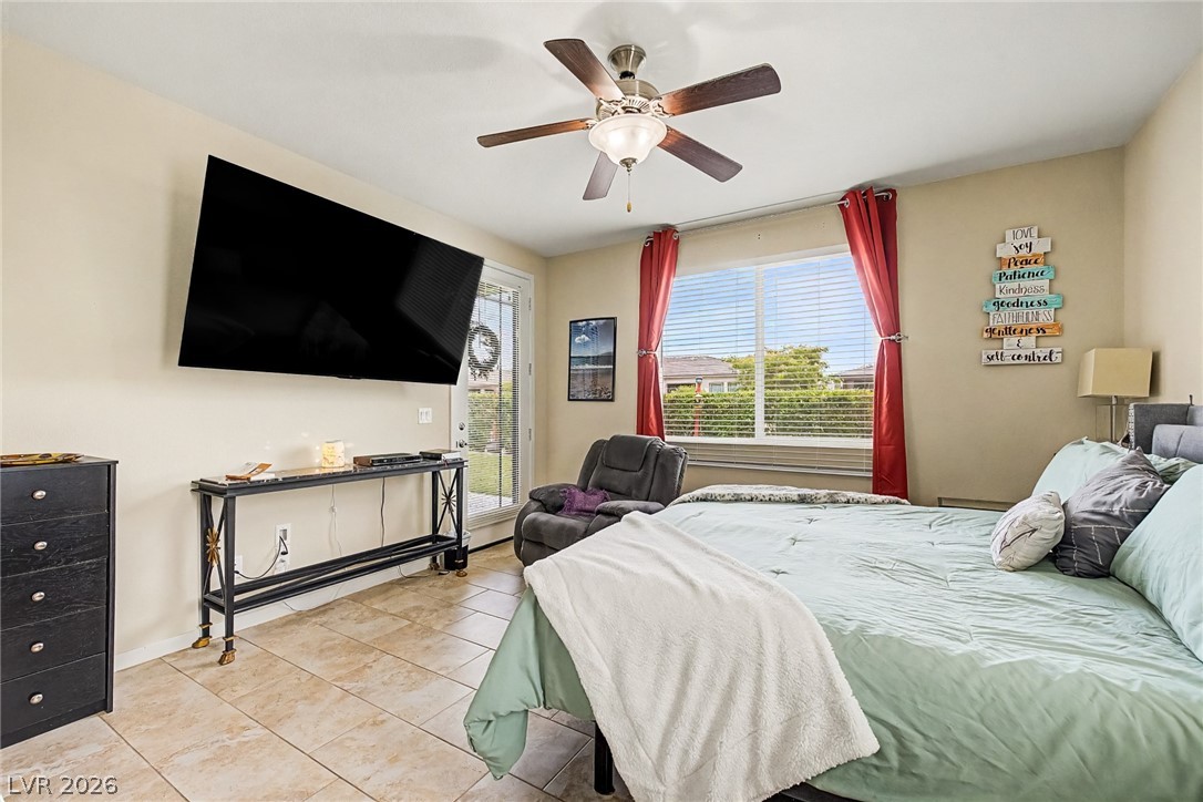 4914 East Beacon Ridge Drive Pahrump, NV 89061 - Photo 17 of 34 A well-lit primary bedroom features tiled flooring and a ceiling fan, offering a comfortable retreat with a private outdoor entry.