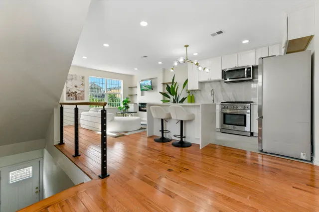 a living room with stainless steel appliances furniture a fireplace a flat screen tv and a kitchen view