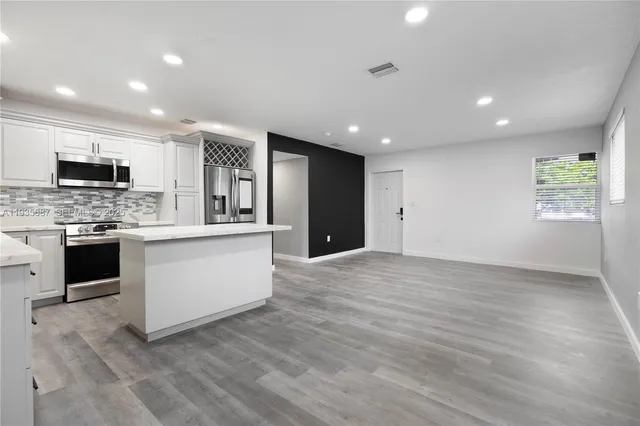 a large kitchen with stainless steel appliances granite countertop a stove a sink and a refrigerator