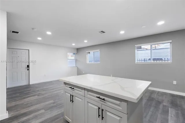 a view of kitchen with granite countertop cabinets and refrigerator