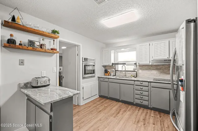 a kitchen with stainless steel appliances a sink cabinets and a window