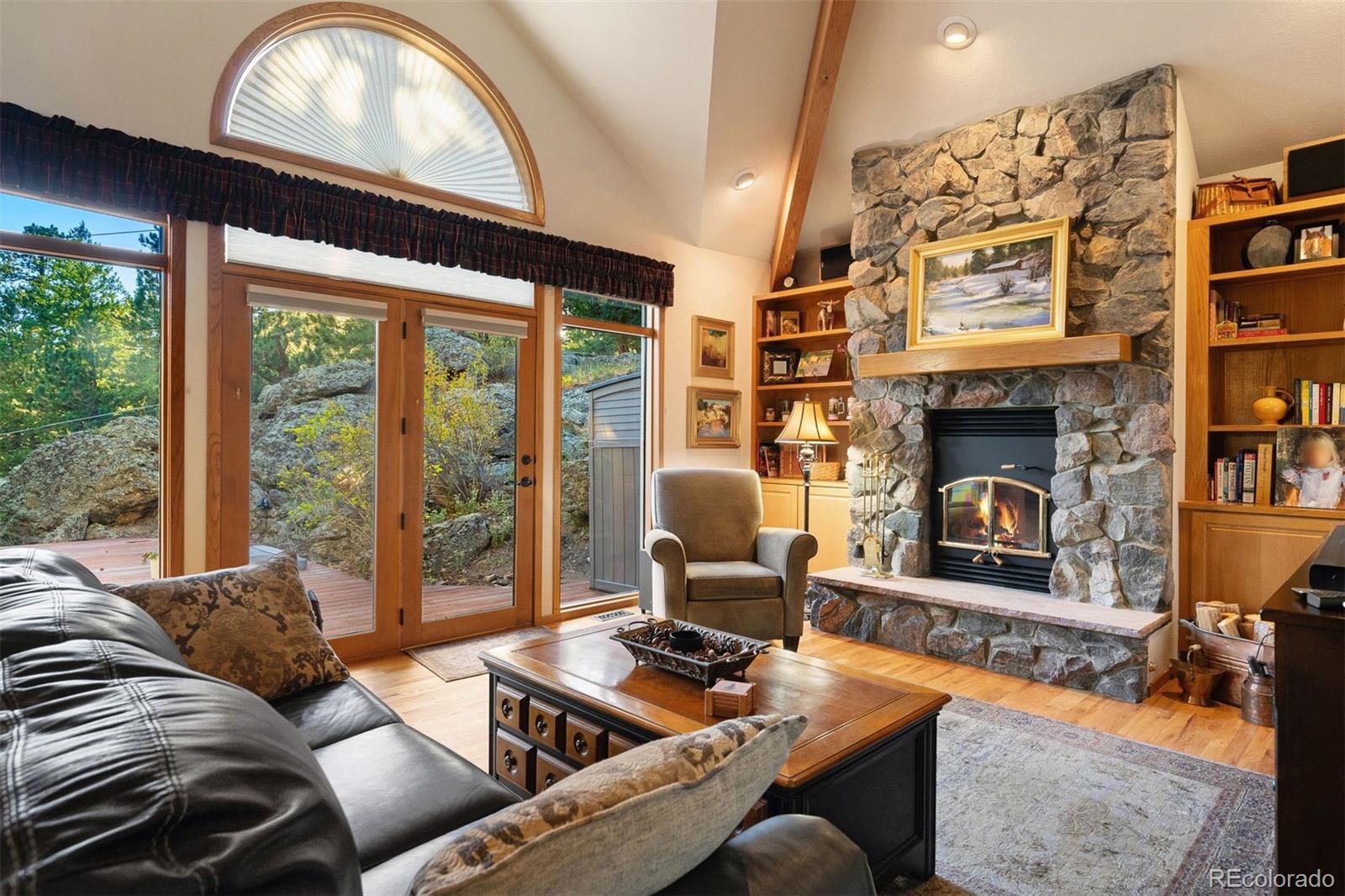 4275 Stonecliff Drive Evergreen, CO 80439 - Photo 14 of 48 a living room with furniture a fireplace and a floor to ceiling window