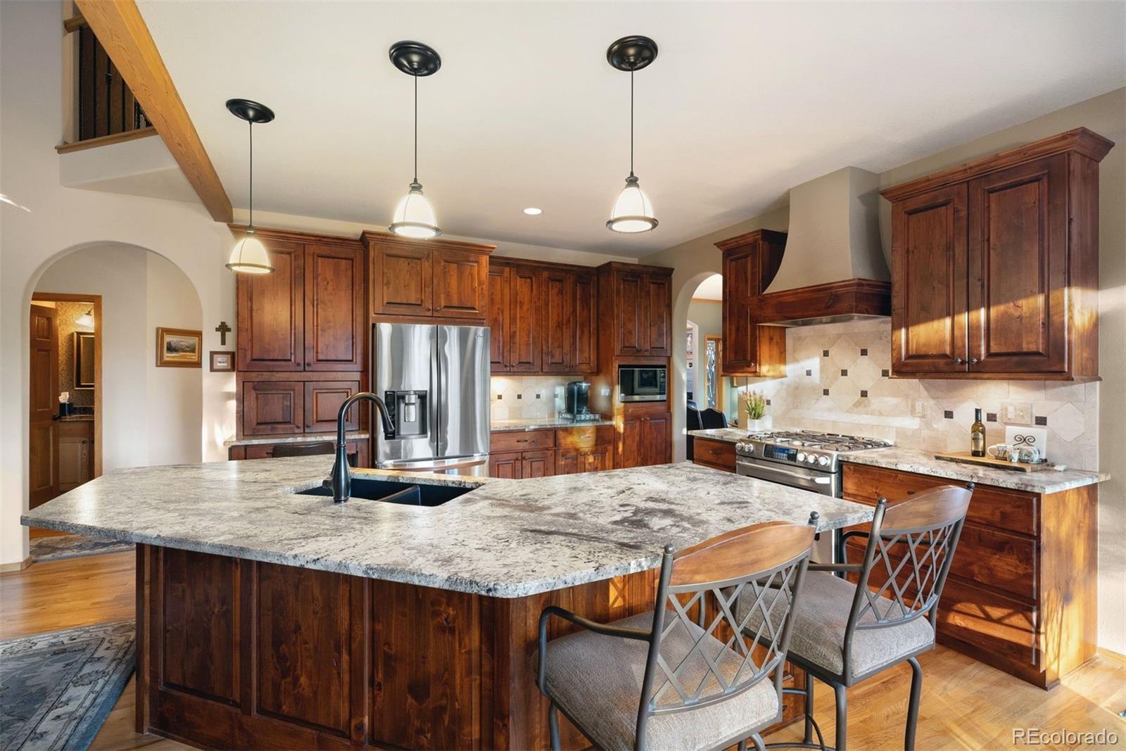 4275 Stonecliff Drive Evergreen, CO 80439 - Photo 17 of 48 a kitchen with granite countertop kitchen island stainless steel appliances a sink and wooden floor