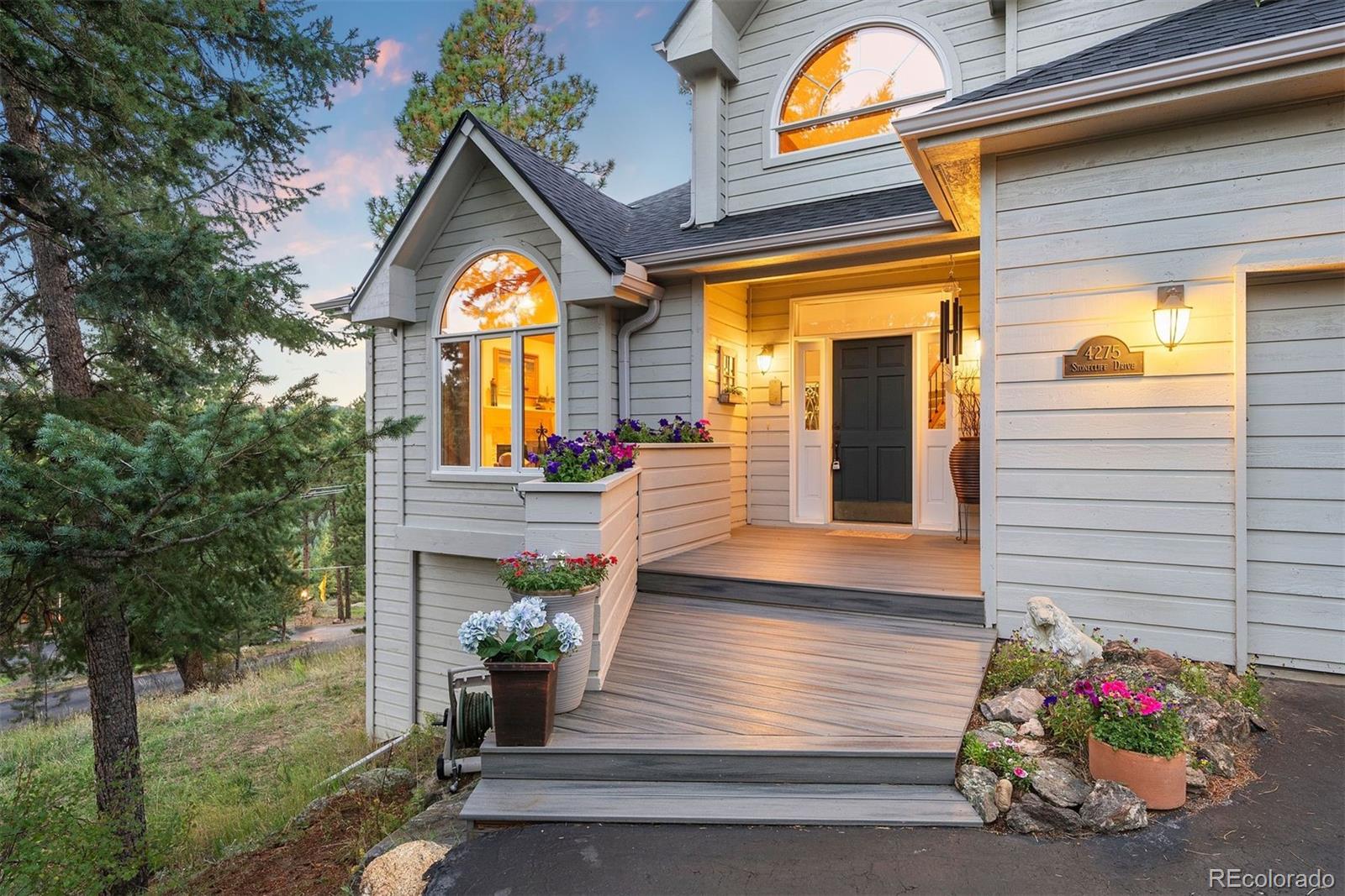 4275 Stonecliff Drive Evergreen, CO 80439 - Photo 6 of 48 a view of a house with large windows and flower plants