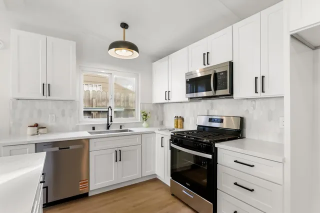 a kitchen with cabinets stainless steel appliances a sink and a window
