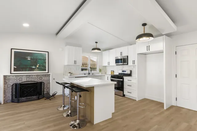 a kitchen with kitchen island a stove a refrigerator and a fireplace