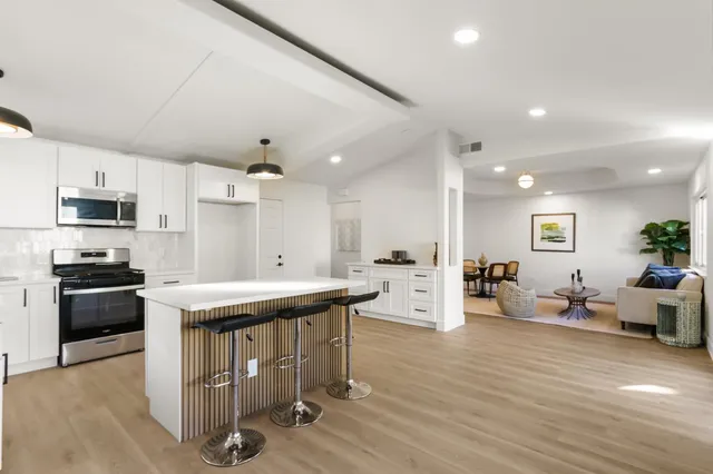 a view of a kitchen with kitchen island a sink stainless steel appliances and cabinets