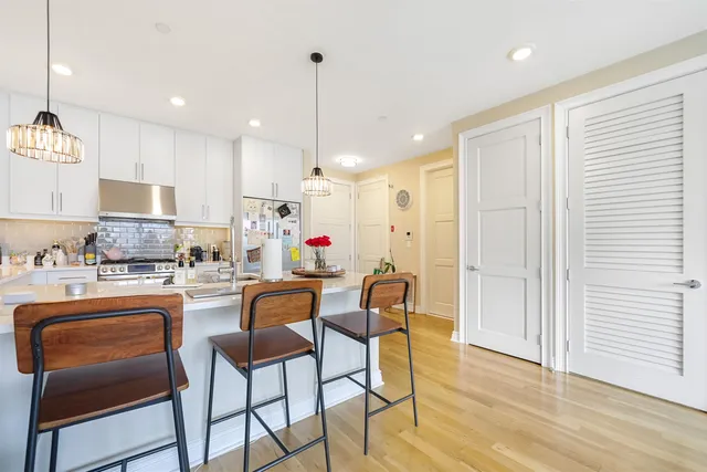 a kitchen with stainless steel appliances granite countertop a stove top oven a refrigerator a sink and chairs