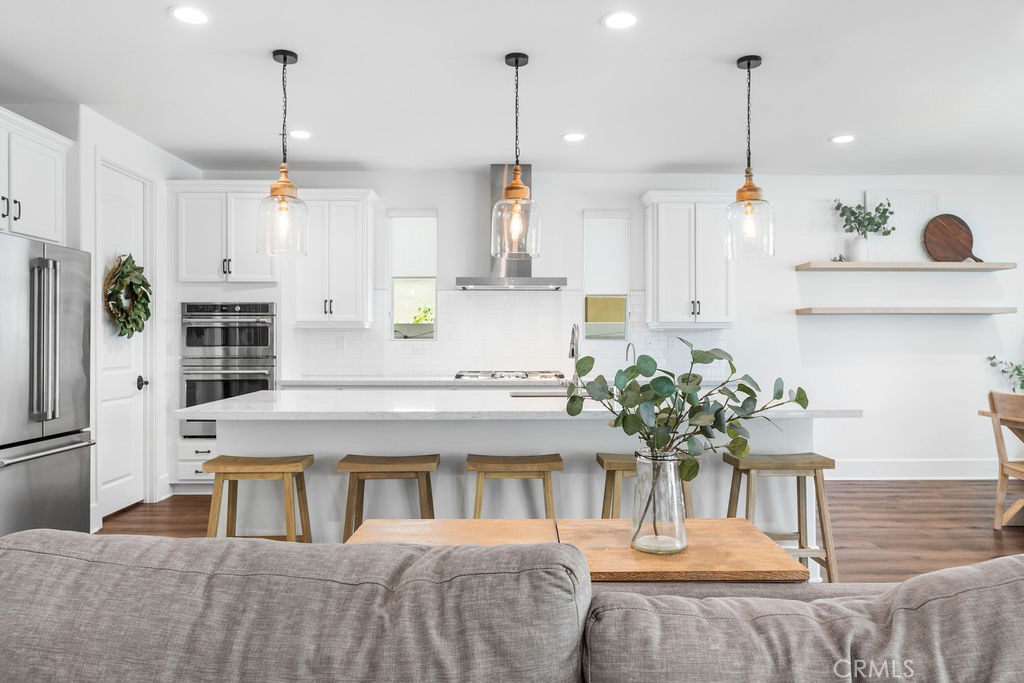 32166 Verbena Way Temecula, CA 92591 - Photo 14 of 47 a kitchen with stainless steel appliances kitchen island granite countertop a refrigerator a stove a dining table chairs and white cabinets