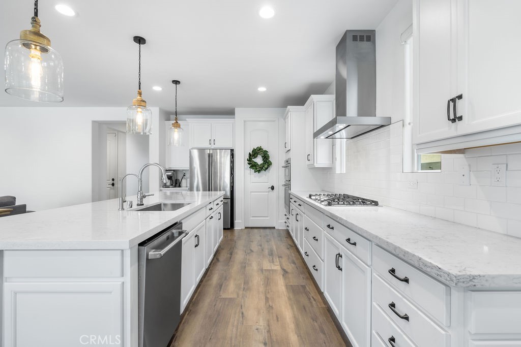 32166 Verbena Way Temecula, CA 92591 - Photo 9 of 47 a large white kitchen with a stove a sink a chimney and cabinets